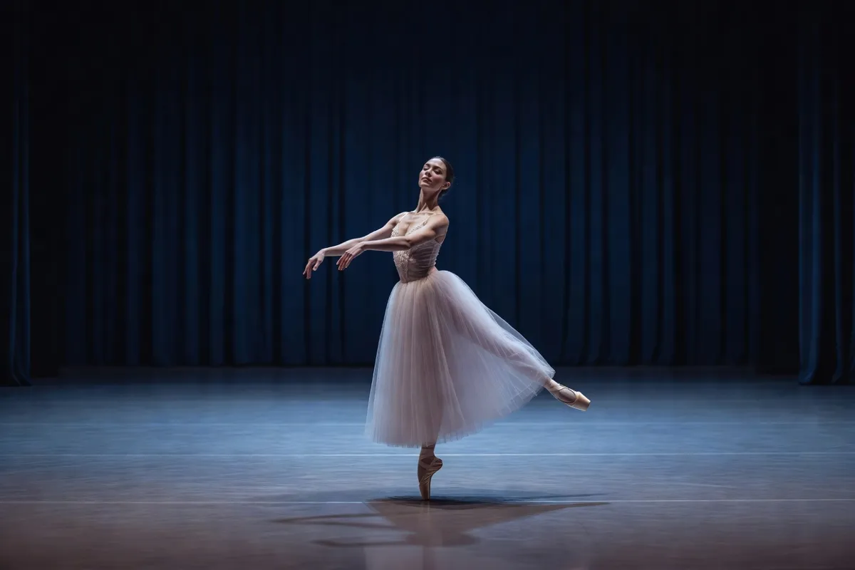 Danseuse en tutu romantique sur une scène de théâtre sous une lumière bleutée
