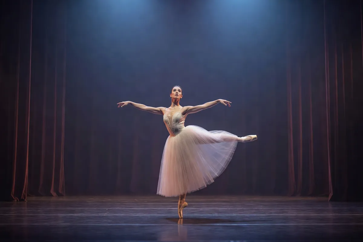 Danseuse en tutu romantique sur une scène de théâtre sous une lumière bleutée